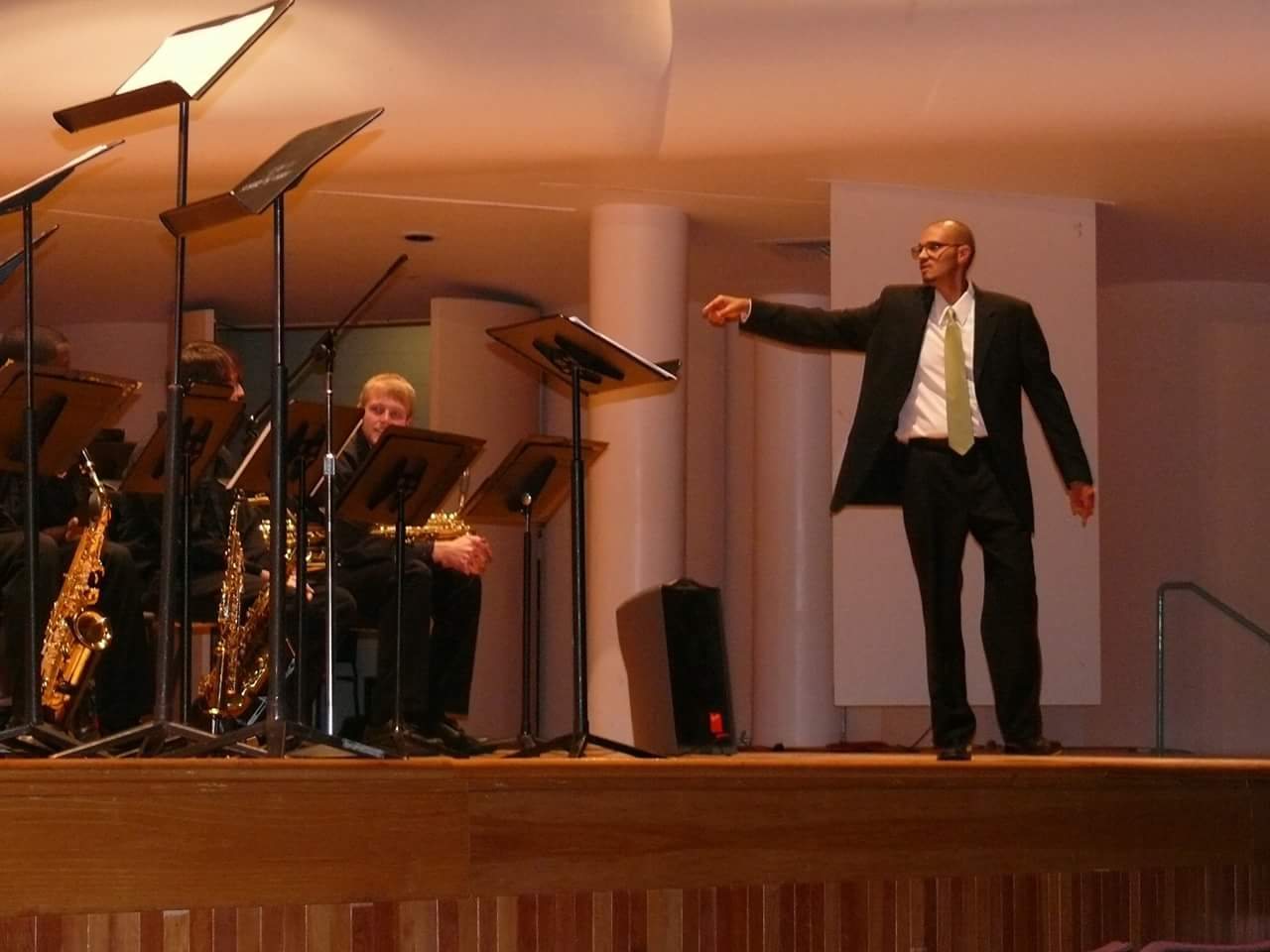 The founder directing the jazz ensemble at the University of Alabama, mid-gesture, green tie on